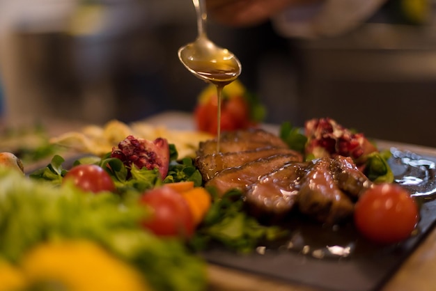 Chefkoch fertigt Steakfleischplatte mit Final Dish Dressing und ist fast servierfertig am Tisch