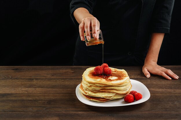 Chefkoch gießt Pfannkuchen mit Honig