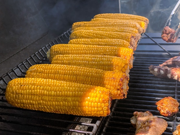 Chefkoch Grill mit einem Maiskolben auf gegrillt. Sehr leckere leckere Hühneraugen auf einem Grill im Hinterhof. Essen gekocht mit Grillen BBQ im Garten eines Hauses.