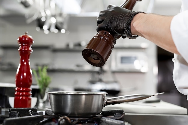 Chefkoch in der Hotel- oder Restaurantküche kocht, er würzt Gerichte