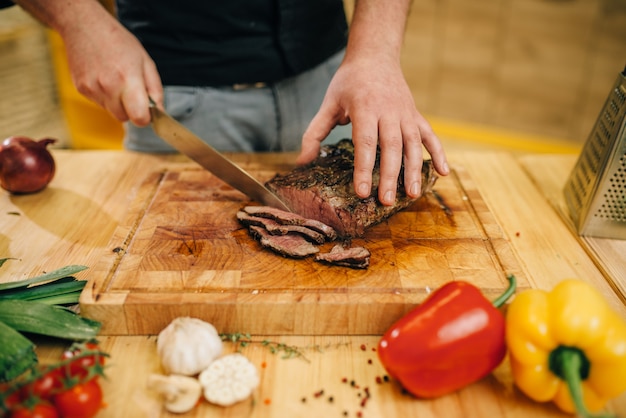 Chefkoch in der Pfanne mit gebratenem Fleisch und Vetables