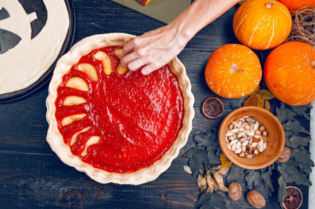 Chefkoch kocht für Halloween eine Torte mit einer Füllung aus Kürbis-Erdbeermarmelade und Pfirsichen