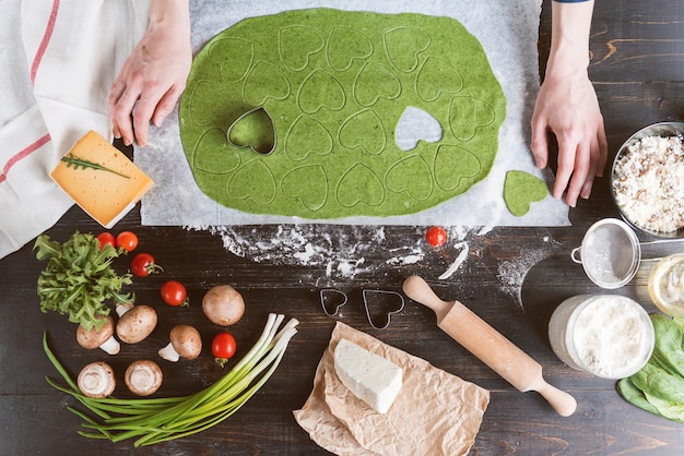 Chefkoch kocht Schritt für Schritt grüne Ravioli in Herzform für ein festliches Abendessen