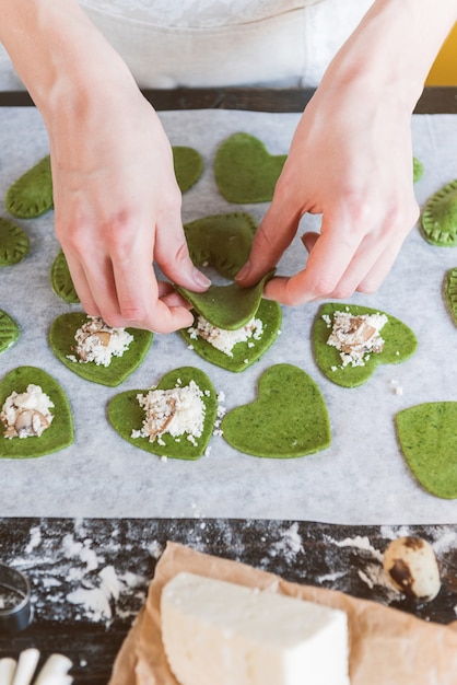 Chefkoch kocht Schritt für Schritt grüne Ravioli in Herzform für ein festliches Abendessen