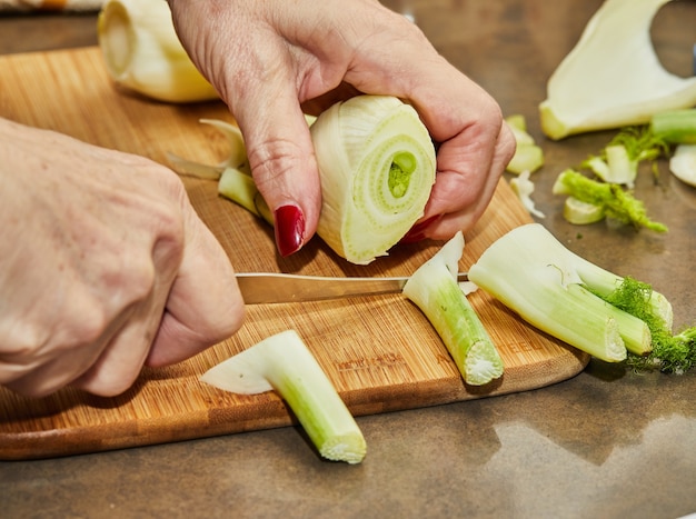 Chefkoch schneidet den Fenchel nach dem Kochrezept auf Holzbrett in der Küche.