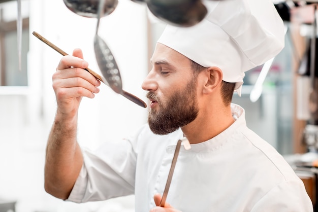 Chefkoch Verkostung von Speisen mit Holzlöffel in der Restaurantküche