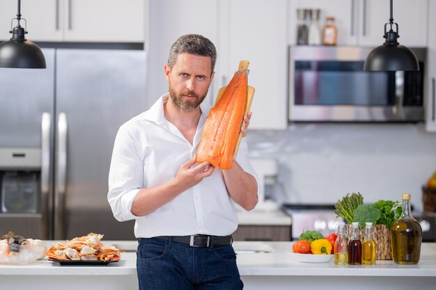 Chefmann, der Meeresfrüchtekrabben und Garnelenlachs und -hummer in der Küche kocht Kochkerl im weißen Hemd auf ki