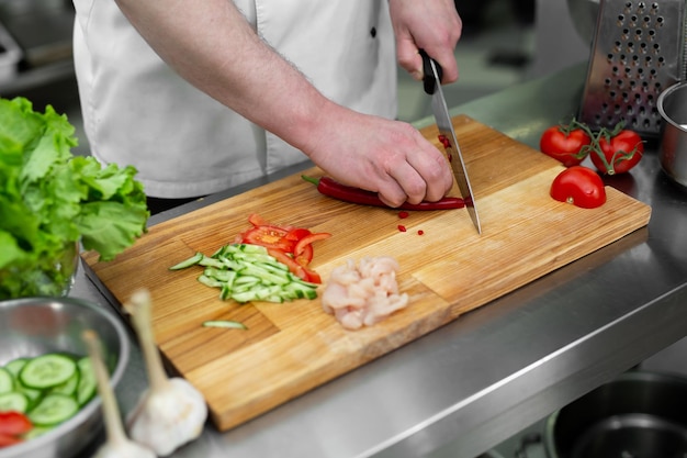 Chefmann schneidet Chilischoten am Tisch in der Nähe