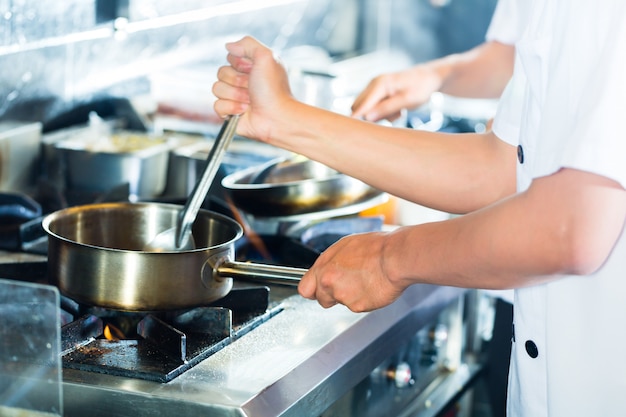 Chefs asiáticos cocinando en restaurante.