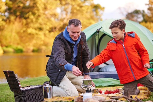 Chefs de campamento en el trabajo Foto de un padre y su hijo preparando una comida mientras acampan