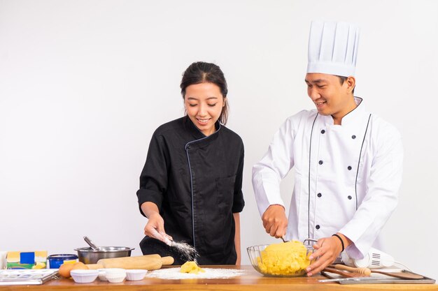 Chefs masculinos e femininos fazendo massa de biscoito juntos na mesa