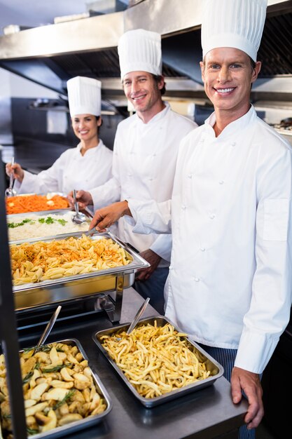 Chefs parados en bandejas de pasta