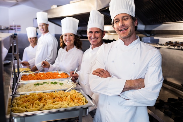 Chefs parados en bandejas de pasta