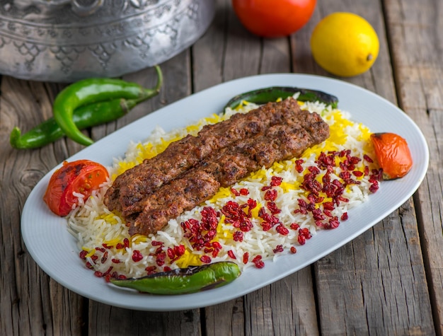 Chelo kebab biryani serviert in tellerseitenansicht auf holztischhintergrund