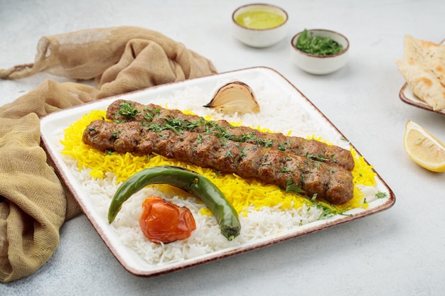 Chelo oder Chelow Kabab mit Reis, Tomate und Limette, serviert in Gerichten, isoliert auf Tischplatte mit Blick auf arabisches Essen