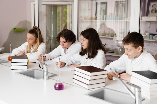 Chemieunterricht im Labor in der Schule Schüler schreiben Hausaufgaben, lächeln und haben gemeinsam Spaß im Schullabor