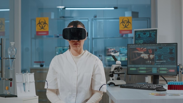 Chemiker, der mit virtual-reality-headset im labor arbeitet und vr-brille verwendet, um wissenschaftliche forschung mit futuristischer 3d-simulation durchzuführen. frau, die eine schutzbrille trägt, um an der mikrobiologischen vision zu arbeiten.