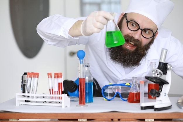 Chemiker verrückt. Ein verrückter Wissenschaftler führt Experimente in einem wissenschaftlichen Labor durch. Führt Forschungen mit einem Mikroskop durch.