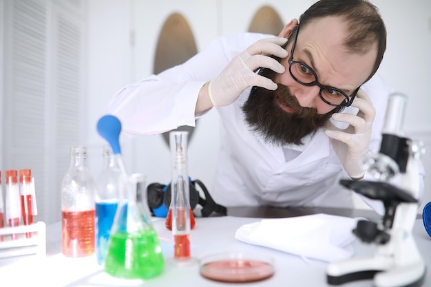 Chemiker verrückt. Ein verrückter Wissenschaftler führt Experimente in einem wissenschaftlichen Labor durch. Führt Forschungen mit einem Mikroskop durch.