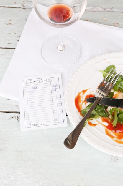 Cheque y restos de ensalada en la mesa en el restaurante