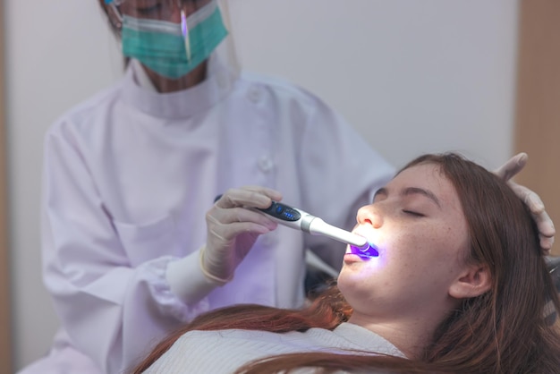 Chequeo de dientes en el dentista, médico que realiza tratamiento dental en una mujer y una niña en el consultorio del dentista