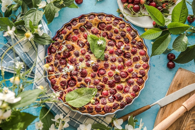 Foto cherry clafoutis con cereza sobre fondo azul.