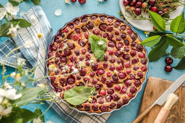 Foto cherry clafoutis con cereza sobre fondo azul.