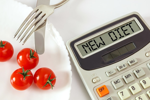 Chery tomates en un plato con cubiertos y una calculadora de calorías