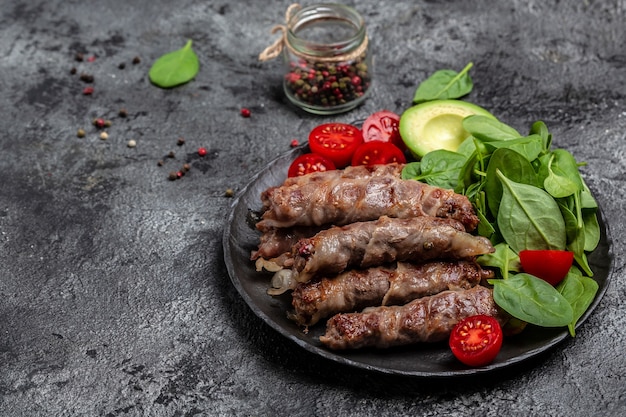 Chevapchichi o Kofta kebab, Carne picada envuelta en tocino con espinacas, aguacate y tomate cherry, Grasas saludables, alimentación limpia para adelgazar. Menú de dieta keto paleo, vista superior,