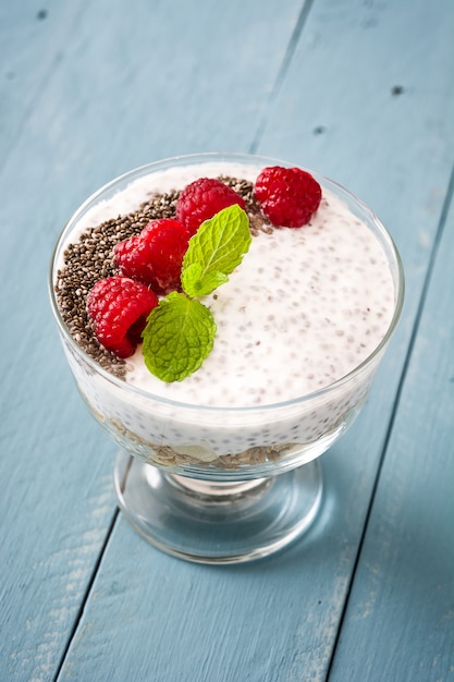 Chia-Joghurt mit Himbeeren auf blauem hölzernem Hintergrund