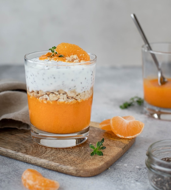 Chia-Joghurt mit Mandarine und Persimone in einem Glas, gesundes Frühstück.