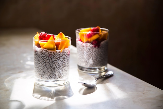 Chia-Pudding auf Kokosmilch mit Himbeeren und Pfirsich in Gläsern