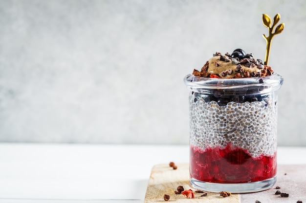 Chia-pudding mit beeren, müsli und erdnussbutter im glas