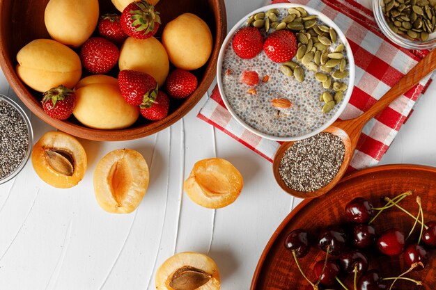 Chia-Pudding mit Erdbeer- und Kürbiskernen auf Holztisch mit Aprikosen