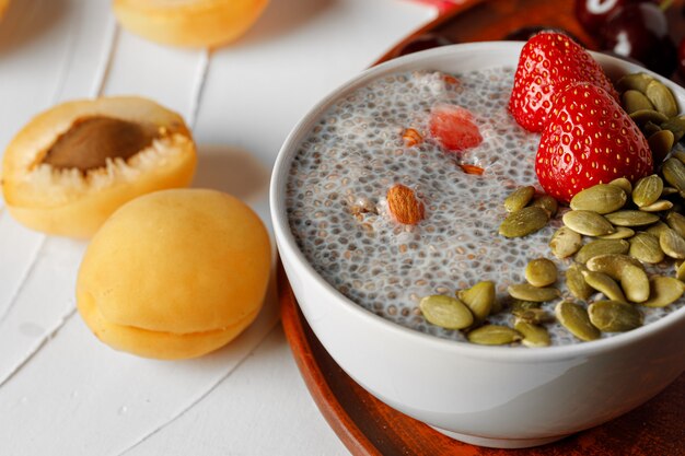 Chia-Pudding mit Erdbeer- und Kürbiskernen auf Holztisch