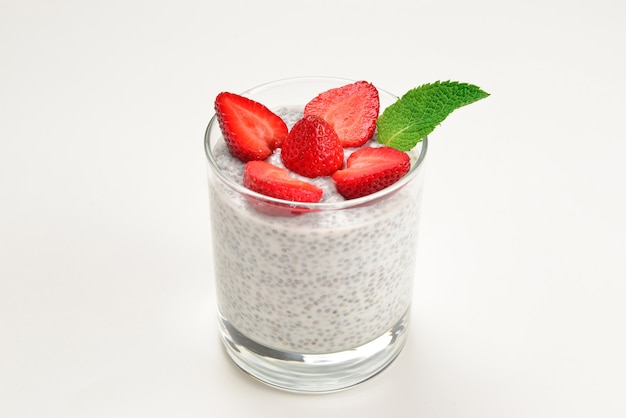 Chia-Pudding mit Erdbeere und Minze an einer weißen Wand. Platz für Text oder Design.