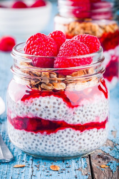 Chia-Pudding mit Himbeer-Sauce-Müsli und frischen Himbeeren auf rustikalem Hintergrund