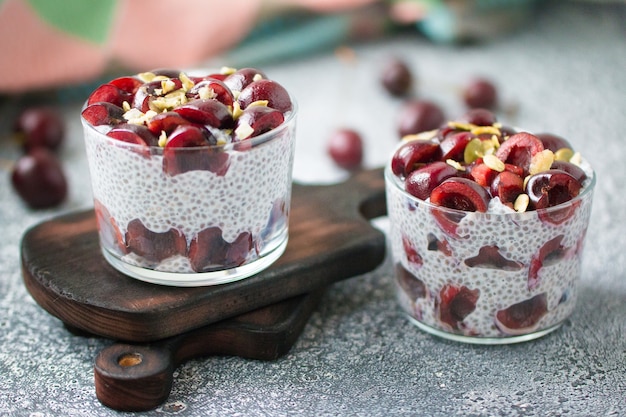 Chia Pudding mit Kirschbeeren Naturjoghurt Chia Kürbiskerne im Glas auf grauer Oberfläche