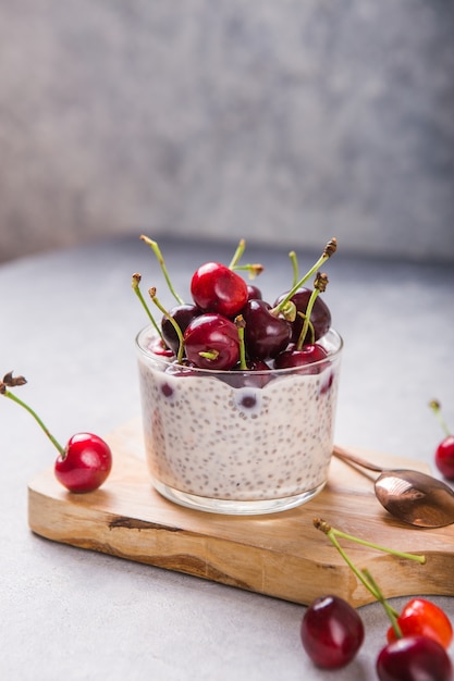 Chia Pudding mit Kirschbeeren, Naturjoghurt, in einem Glas auf einer grauen Oberfläche