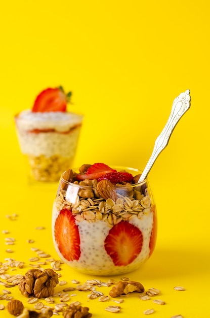 Chia pudim de iogurte com morangos, farinha de aveia e nozes em um copo amarelo