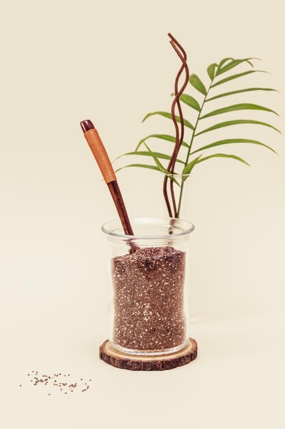 Chia-Samen in einem Glaskrug mit einem Holzlöffel ein Palmblatt auf einem hellen Hintergrund mit Kopierplatz
