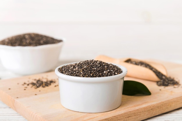 Chia-Samen in Schüssel und Löffel auf farbigem Hintergrund Gesundes Salvia hispanica in kleiner Schüssel Gesundes Superfood