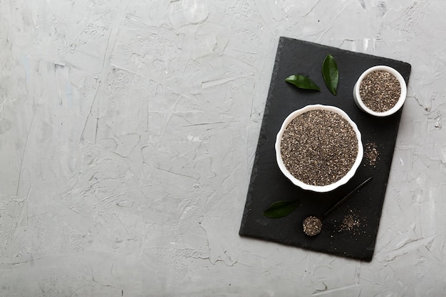 Chia-Samen in Schüssel und Löffel auf farbigem Hintergrund Gesundes Salvia hispanica in kleiner Schüssel Gesundes Superfood