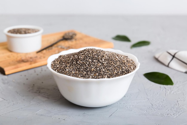 Chia-Samen in Schüssel und Löffel auf farbigem Hintergrund Gesundes Salvia hispanica in kleiner Schüssel Gesundes Superfood