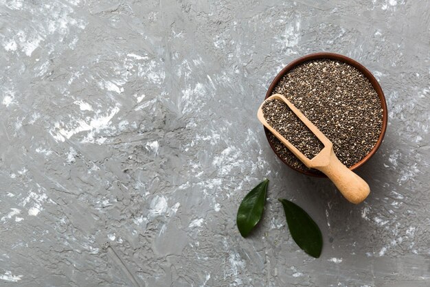 Chia-Samen in Schüssel und Löffel auf farbigem Hintergrund Gesundes Salvia hispanica in kleiner Schüssel Gesundes Superfood