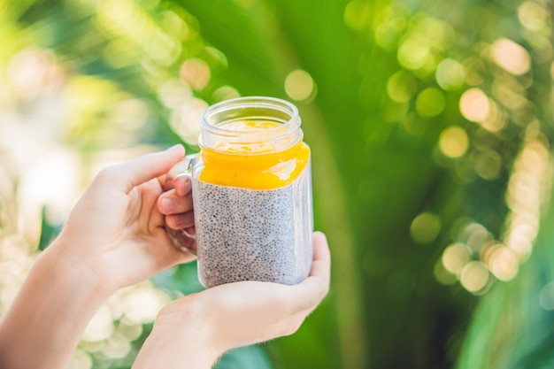 Chia-Samen-Pudding mit Mandelmilch und frischem Mango-Topping in der Hand