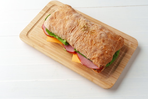 Chiabatta-Sandwich mit Schinken und Käse auf Holzbrett