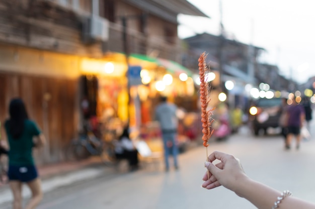 Chiang Khan Walking Street: gente de la calle caminando con brochetas de camarón desmenuzado con fondo borroso