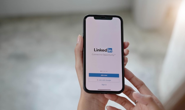 CHIANG MAI TAILANDIA 12 DE JULIO DE 2022 Una mujer sostiene Apple iPhone Xs con la aplicación LinkedIn en la pantalla LinkedIn es una aplicación para compartir fotos para teléfonos inteligentes