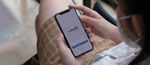CHIANG MAI, TAILÂNDIA, 14 DE NOVEMBRO DE 2021: Uma mulher segura o Apple iPhone Xs com o aplicativo LinkedIn na tela.LinkedIn é um aplicativo de compartilhamento de fotos para smartphones.